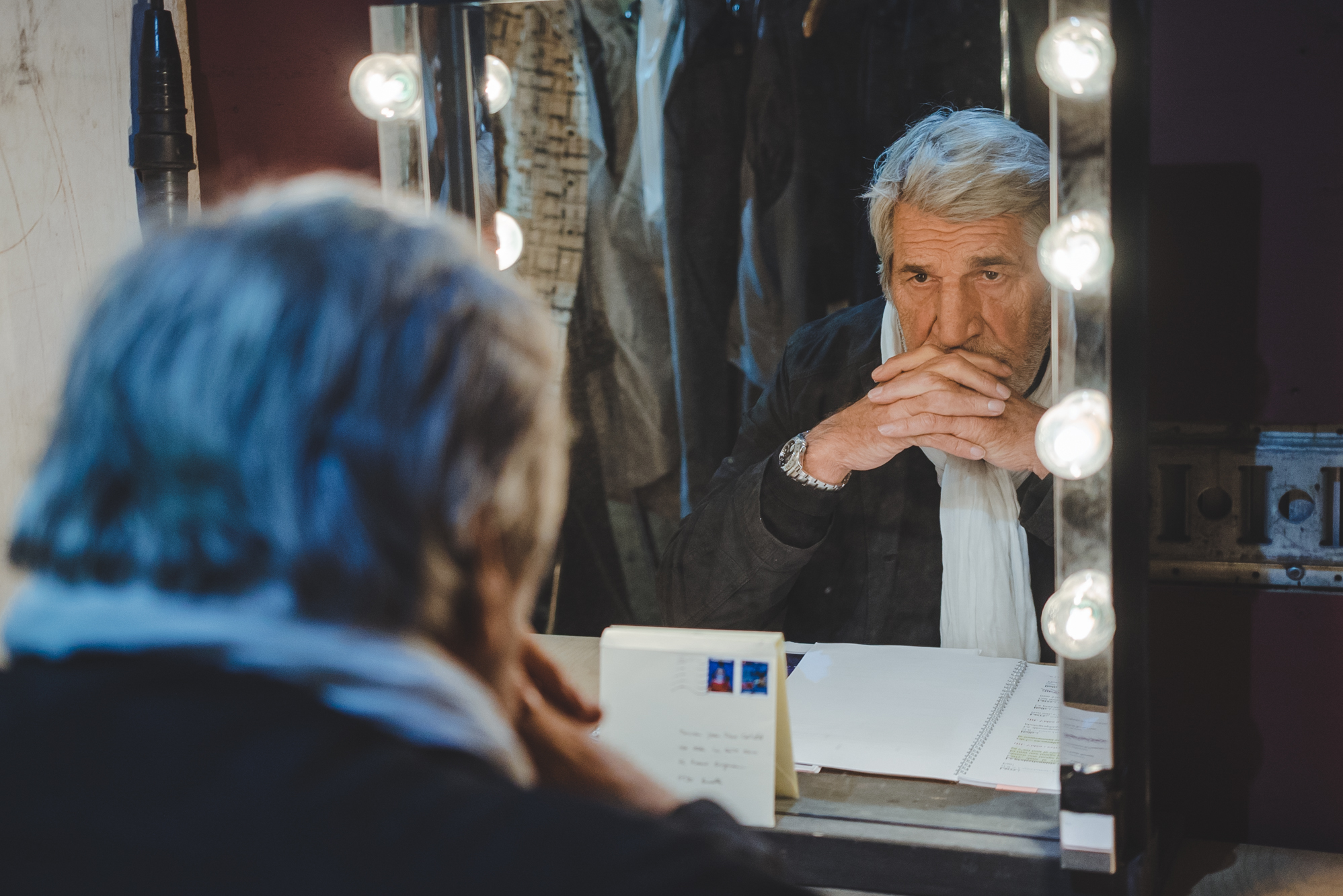 Dans les coulisses, un comédien se prépare devant son miroir